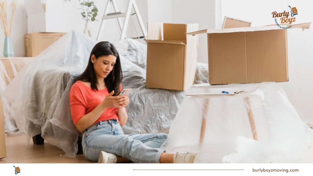 Woman surrounded by boxes and checking house moving apps for assistance